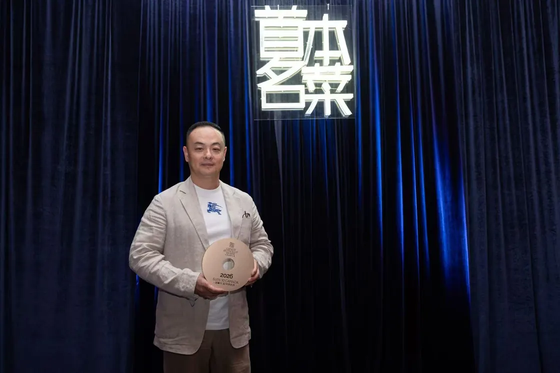 Yuan's Garden's representative holding the round gold Elite 30 Canada 2026 trophy beside the neon 首本名菜 sign of the Chinese Restaurant Awards