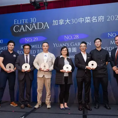 Award recipients holding their trophies on stage beneath a screen reading Elite 30 Canada 加拿大30中菜名府 2026, with Yuan's Garden 隨園 among the names