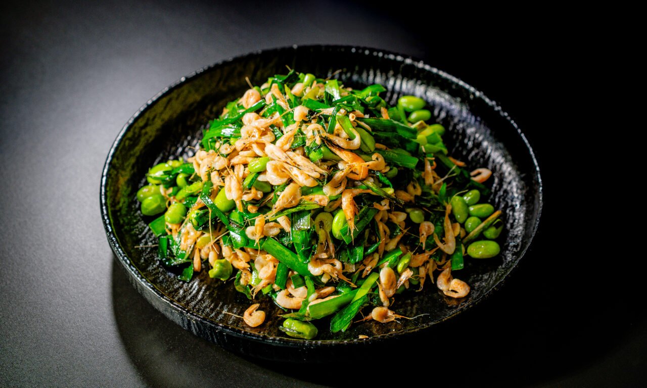 Stir-fried river shrimp with chives and edamame in a black bowl