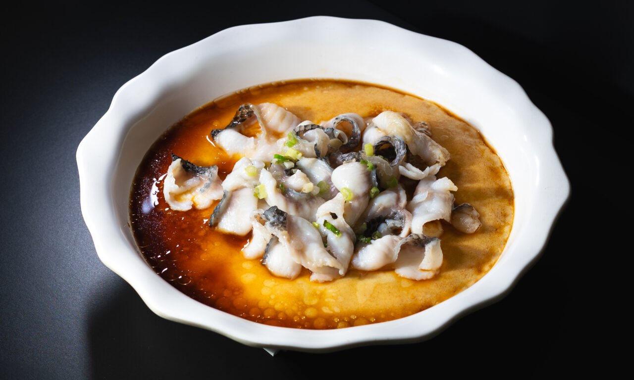 Tender poached fish fillet in a golden house broth