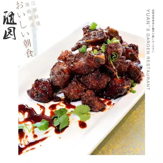 Glossy red-braised ribs, scattered with spring onion